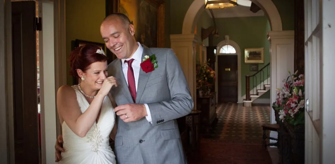 A wedding couple sharing a joke in the front entrance hall.